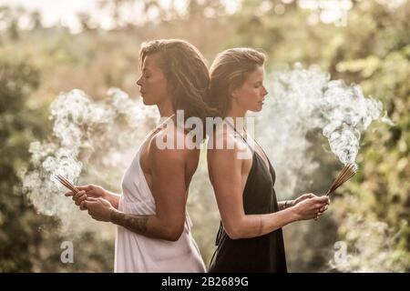 Deux filles debout avec de l'encens au coucher du soleil. Banque D'Images