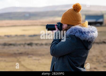 Jeune femme utilisant un appareil photo numérique, Valentia Island, County Kerry, Irlande Banque D'Images