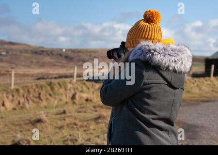 Jeune femme utilisant un appareil photo numérique, Valentia Island, County Kerry, Irlande Banque D'Images