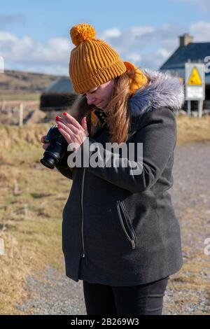 Jeune femme utilisant un appareil photo numérique, Valentia Island, County Kerry, Irlande Banque D'Images