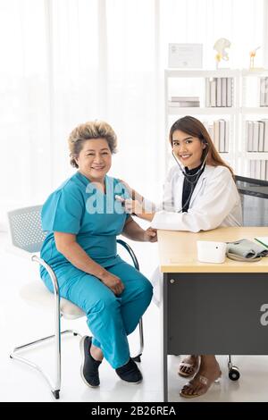 Médecin à l'écoute des personnes âgées femme souffle avec un stéthoscope au bureau de la salle d'examen à l'hôpital clinique. Banque D'Images