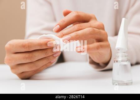 gros plan femme mains enlever la peinture des ongles avec le tampon de coton Banque D'Images