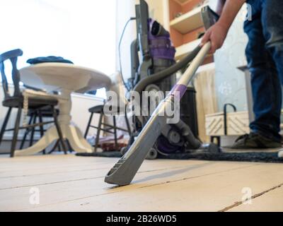 Un homme moderne qui passe l'aspirateur sur les sols Banque D'Images