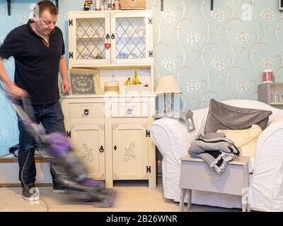 Un homme moderne qui passe l'aspirateur sur les sols Banque D'Images