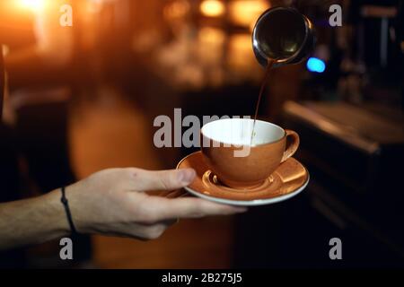 méthode de préparation: guy verser du café froid, gros plan de la photo, latte tomber dans la tasse, homme va prendre le petit déjeuner Banque D'Images