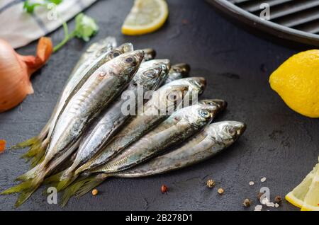 Délicieux poisson frais, herbes aromatiques, épices et citron sur fond noir.cuisine méditerranéenne. Vue de dessus. Concept de nourriture saine et diététique. fi brut Banque D'Images