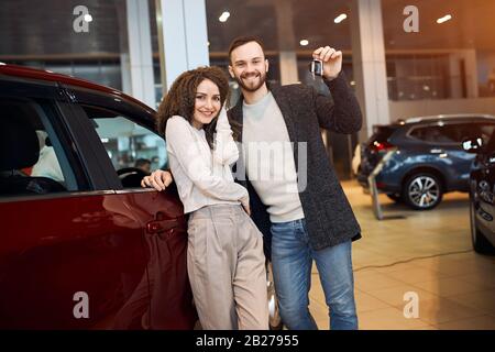 bonne famille séduisante collectant une nouvelle voiture du lot, gros plan photo Banque D'Images