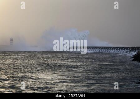 Une grande vague éclabousser sur la jetée au coucher du soleil. Bouche du Douro. Banque D'Images