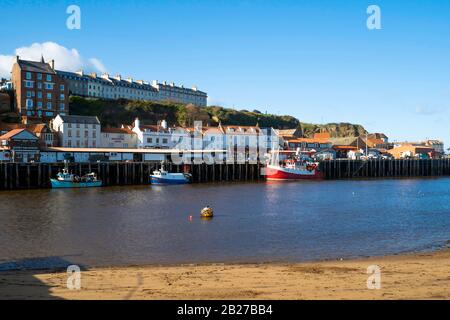 Bateaux de pêche bleus et rouges attachés au quai à poissons dans le port de Whitby North Yorkshire. Banque D'Images