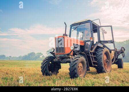 le vieux tracteur fertilise dans le champ dans un beau temps bleu ensoleillé Banque D'Images