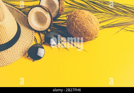 Composition estivale avec lampes au néon. Feuilles de palmiers tropicales, chapeau, verres et noix de coco cassée sur un fond sablonneux. Le concept de la saison estivale Banque D'Images