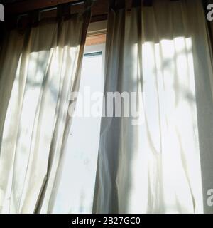 Vue en bas angle d'une lumière du matin à travers les rideaux sur une fenêtre Banque D'Images