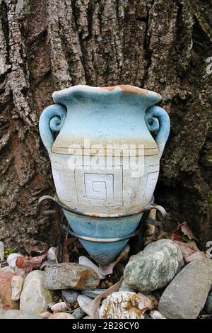 Vase en terre cuite en forme d'amphora avec texture d'arbre comme fond et pierres décoratives en face. Un détail du jardin du monastère Banque D'Images
