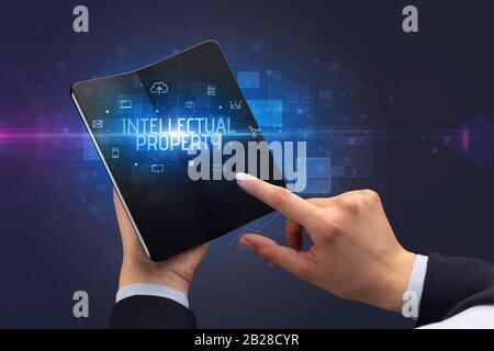 Businessman holding a smartphone pliable avec inscription de la propriété intellectuelle, la cyber sécurité concept