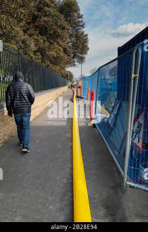 Ramsgate, Angleterre - 25 février 2020 un nouveau tuyau de gaz jaune étiré le long d'un pavé alors qu'il est alimenté sous terre. Un piéton est à pied. Banque D'Images