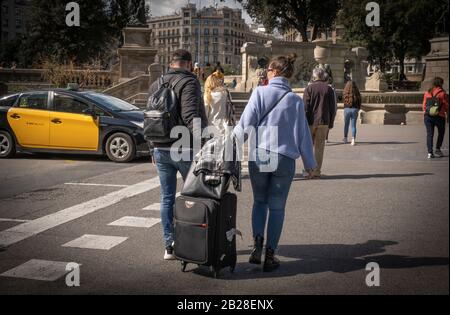 Les touristes tenant leurs valises se rendent à l'arrêt AeroBus pour l'aéroport Prat de Barcelone. Le Ministère de Salut rapporte de nouveaux cas de coronavirus dans la communauté autonome de Catalogne (Espagne) augmentant le nombre à douze affectés. Le nombre de touristes à Barcelone présente un profil bas. Les masques hygiéniques commencent à être un élément plus fréquent parmi la population. Banque D'Images