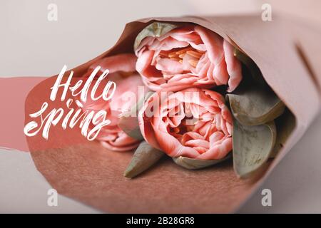 Bonjour carte de printemps. Un bouquet de trois tulipes dans un emballage en papier repose sur une table. Banque D'Images