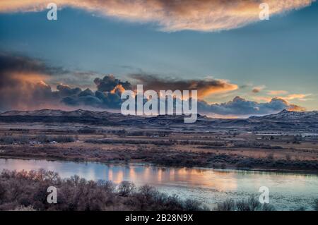 Soleil sombre et sombre ciel couvert couvert de nuages illuminés en fin de soirée en regardant la rivière Snake avec la chaîne de montagnes Owyhee dans le lointain en Id Banque D'Images