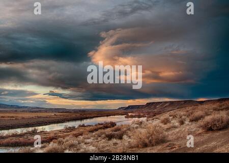 Sombre et sombre soleil illuminé nuage couvert ciel en fin de soirée regardant sur la rivière Snake avec beaucoup de mesas dans le lointain en Idaho Banque D'Images