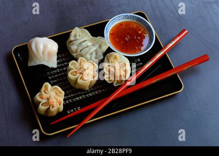 Dim Sum, boulettes remplies sur plateau avec baguettes rouges et sauce Chili, Allemagne Banque D'Images