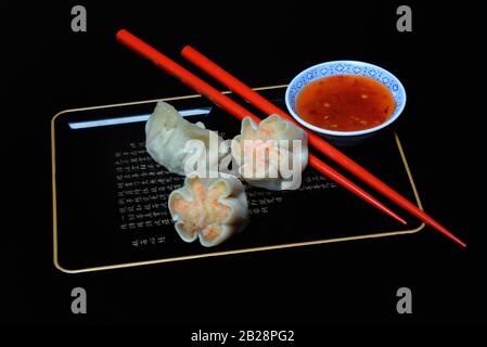 Dim Sum, boulettes remplies sur plateau avec baguettes rouges et sauce Chili, Allemagne Banque D'Images