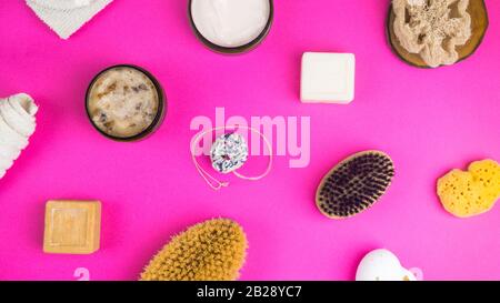 Gommage, lotion, savons, serviette en coton, gant exfoliant pour le soin du corps sur fond rose. Kit spa écologique, plat Banque D'Images