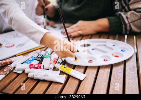 Une petite fille avec ses grands-parents peindre quelques dessins sur la terrasse de sa maison avec de la peinture aquarelle Banque D'Images