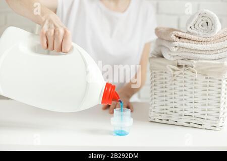 Femme qui verse du détergent dans le bouchon de la table, gros plan. Concept de blanchisserie Banque D'Images