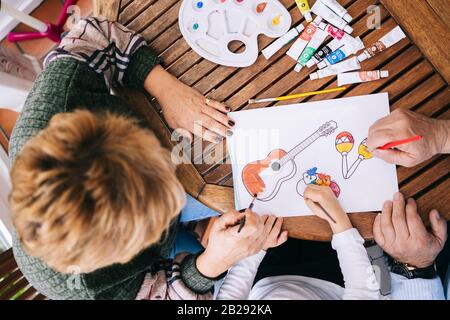 Une petite fille avec ses grands-parents peindre quelques dessins sur la terrasse de sa maison avec de la peinture aquarelle Banque D'Images