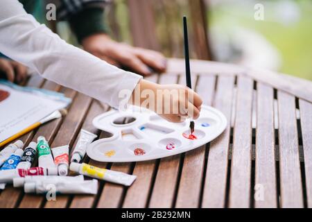 Une petite fille avec ses grands-parents peindre quelques dessins sur la terrasse de sa maison avec de la peinture aquarelle Banque D'Images