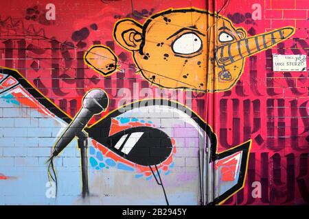 Graffitis moderne Dans La Via Sturzo, Milan, Italie, représentant la caricature d'un visage humain avec un grand nez et un étranger avec un microphone de stand Banque D'Images