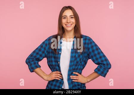 Portrait d'une fille bien dénaturée dans un maillot à carreaux souriant sincèrement à l'appareil photo, tenant les mains sur les hanches, regardant confiant et content de la vie, réjouissant Banque D'Images