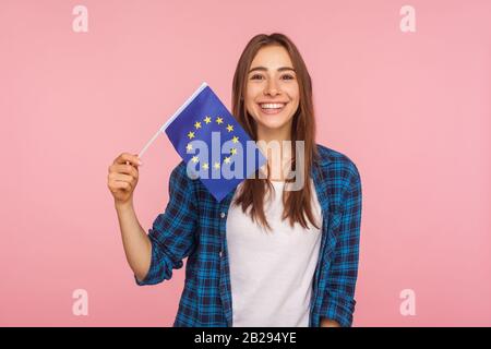 Portrait d'une jolie femme sympathique dans une chemise à damier souriant largement et tenant drapeau de l'Union européenne, symbole de l'Europe, de l'association européenne et de la communication Banque D'Images