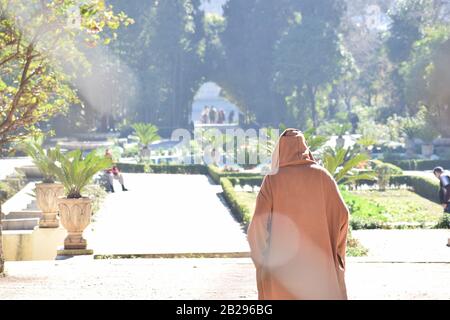 Un homme marocain âgé traverse des jardins dans une Djellaba Banque D'Images