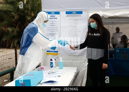 Tel Aviv, Israël. 1 mars 2020. Les membres du personnel montrent comment voter dans un bureau de vote spécial pour les électeurs mis en quarantaine en raison de l'exposition au coronavirus, dans la ville israélienne centrale de tel Aviv, le 1er mars 2020. Israël se préparait dimanche à des élections parlementaires répétées sans précédent lundi, pour la troisième fois en moins d'un an. Quelque 14 bulletins de vote spéciaux seront établis pour l'utilisation de centaines d'Israéliens qui sont soumis à l'autoquarantaine obligatoire par crainte qu'ils aient été infectés par la COVID-19. Crédit: Xinhua/Alay Live News Banque D'Images