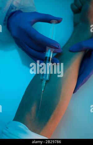 Gros plan sur la seringue d'insertion médique dans la veine du bras masculin tout en donnant un vaccin ou une dose de traitement, copier l'espace Banque D'Images