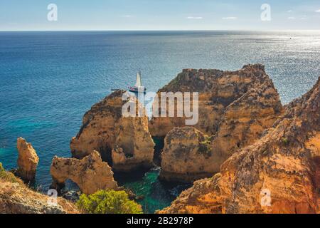 Magnifique paysage marin avec rochers et falaises et yacht à Ponta da Piedade, région de l'Algarve, Portugal, Europe Banque D'Images