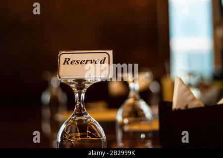 Étiquette réservée sur la table du restaurant avec un beau verre et un fond bokeh Banque D'Images