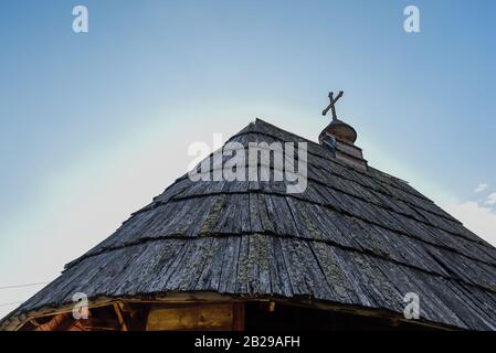 Toit en bois de refuge construit à partir de foin avec croix sur le dessus comme église médiévale en Serbie, une journée ensoleillée contre le ciel bleu Banque D'Images