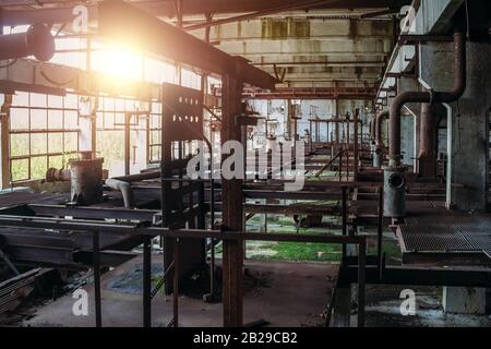 Ancienne usine abandonnée avec restes rouillés de machines industrielles en atelier. Banque D'Images