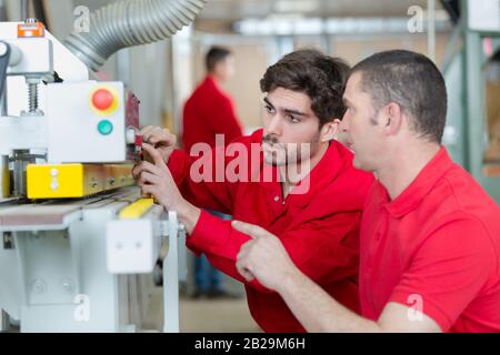 employé stagiaire qui demande au contremaître les commandes de machines Banque D'Images