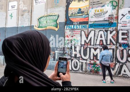 Les jeunes femmes photographiaient des œuvres d'art sur le mur de séparation à Bethléem, en Palestine Banque D'Images