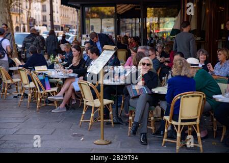 Les gens qui ont du café à l'extérieur peuvent s'asseoir dans un café à Paris, en France Banque D'Images