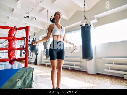 Belle femme de fitness sautant la corde dans la salle de gym. Entraînement cardio et fitness. Concept sportif Banque D'Images