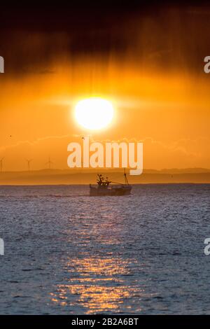 Mousehole, Cornwall, Royaume-Uni. 2 mars 2020. Un bateau de pêche isolé de Newlyn part devant le Lizard pensinula au lever du soleil, avec des nuages de tempête au-dessus. Crédit Simon Maycock / Alay Live News. Banque D'Images