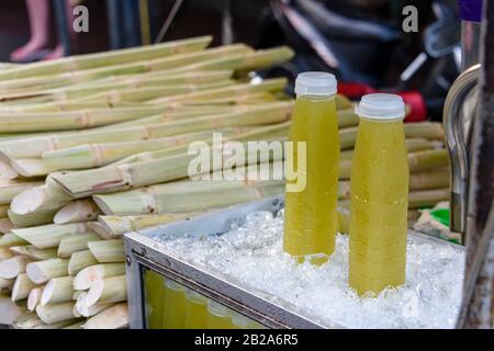 Bouteilles en plastique sur glace contenant de la canne à sucre en pâte à vendre sur un stand de rue, Bangkok, Thaïlande Banque D'Images