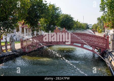 Fontaines au-dessus du canal avec un pont en fonte rouge, Wat Benchamabophit (le temple de marbre), Bangkok, Thaïlande Banque D'Images