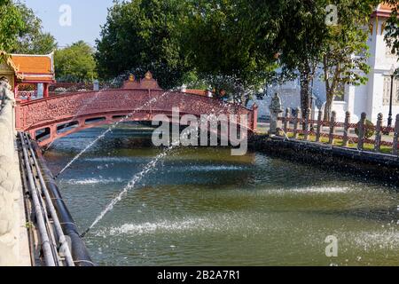 Fontaines au-dessus du canal avec un pont en fonte rouge, Wat Benchamabophit (le temple de marbre), Bangkok, Thaïlande Banque D'Images