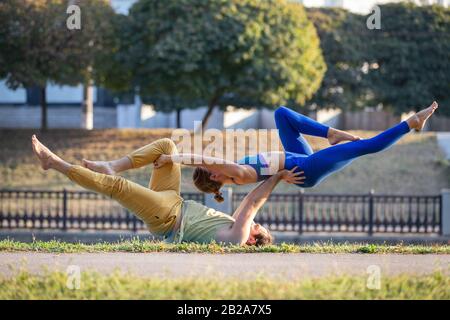 Un jeune couple de fitness fait de l'acroyoga dans le parc le matin. Banque D'Images