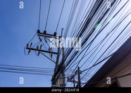 Câbles électriques désordonnés et désordonnés accrochés à un poteau électrique en Thaïlande Banque D'Images